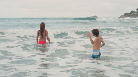 Lächelnde-Teenager-Schwimmen-Am-Meer.-Glückliche-Kinder,-Die-In-Wellen-Spielen.
