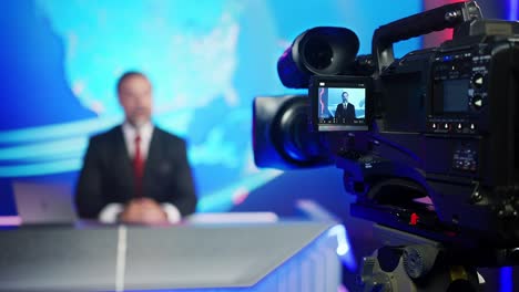 professional tv camera standing in live news studio with anchor seen in small display. unfocused tv broadcasting channel with presenter, newscaster talking. mock-up television channel newsroom set