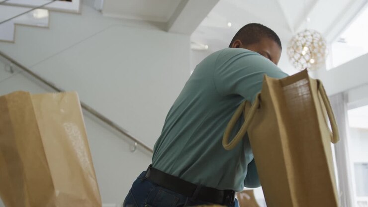 Happy african american plus size woman unpacking shopping bags in kitchen