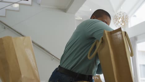 Happy african american plus size woman unpacking shopping bags in kitchen