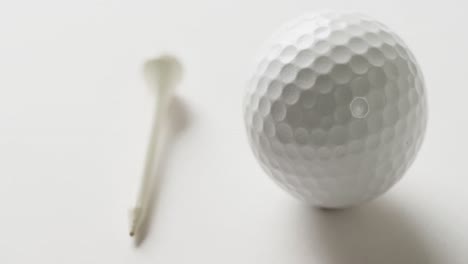 primer plano del tee de golf y la pelota sobre un fondo blanco, espacio de copia, cámara lenta