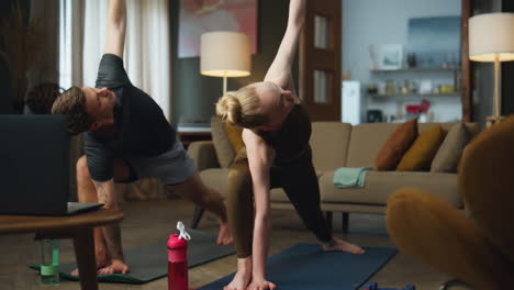 couple making yoga pose on sport mat at home. family practicing triangle asana.