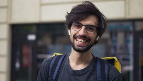 hombre joven sonriente del servicio de entrega de alimentos con una gran mochila térmica