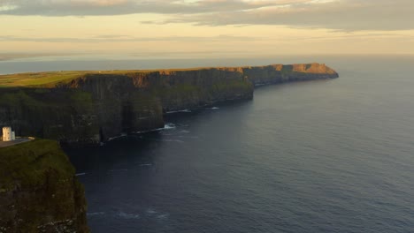 aerial pullback showcases cliffs of moher in warm sunrise light