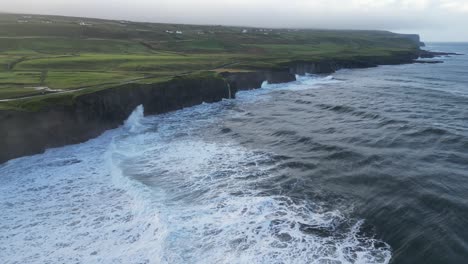 aerial dolly shot towards a small waterfall on the doolin cliffs, ireland