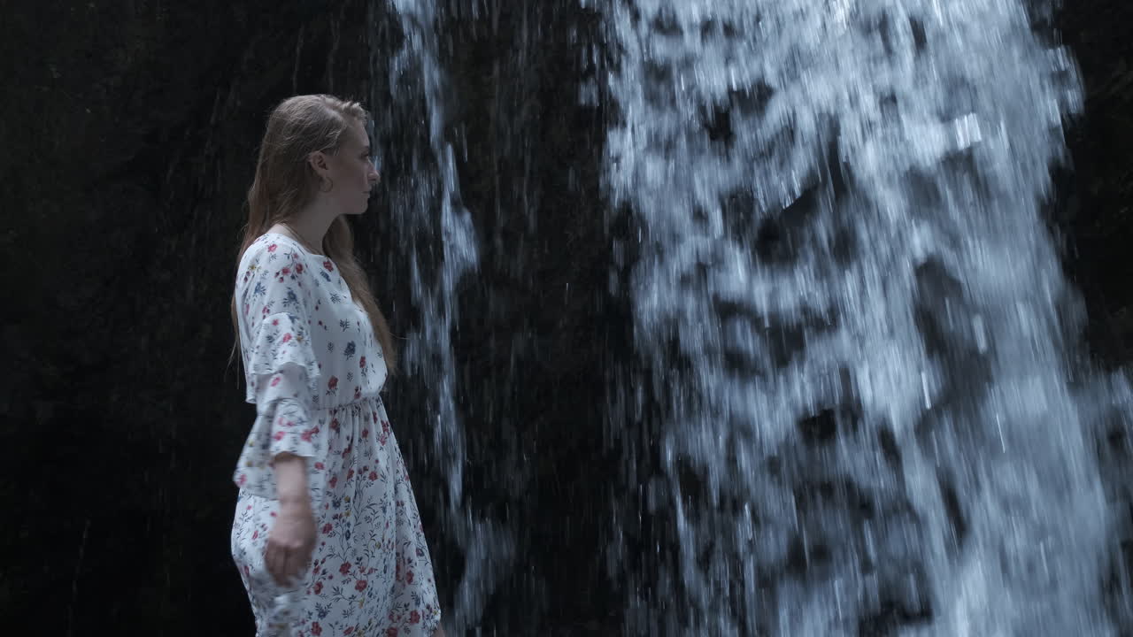 Young woman interacting with a powerful waterfall