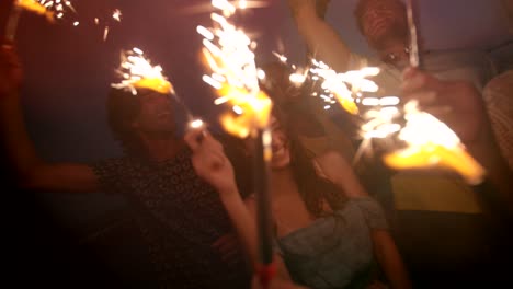 jovens hipsters multiétnicos celebrando com fogos de artifício na festa noturna