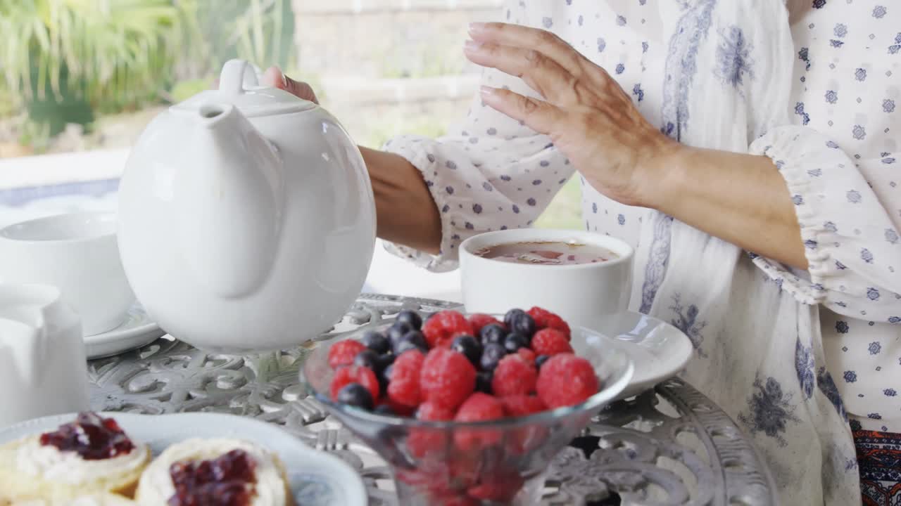 mujer madura vertiendo té de limón en una taza 4k