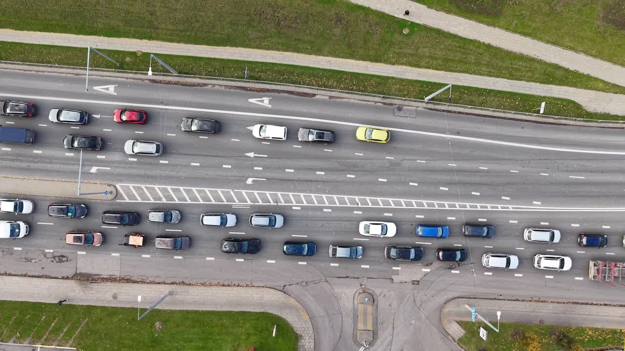 Vista statica dall'alto con drone del traffico intenso a Vilnius, che mostra una strada a più corsie bloccata, veicoli che si immettono e auto che svoltano all'incrocio.