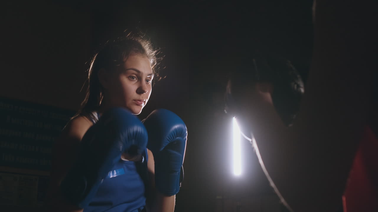 Pugilessa che colpisce i colpitori con i guantoni da boxe in una palestra fumosa