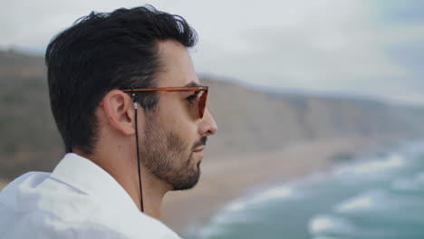 Sunglasses man watching marine horizon closeup. Thoughtful tourist enjoying sea
