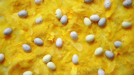 Composition-of-pastel-easter-eggs-lie-among-of-yellow-feathers-for-holidays