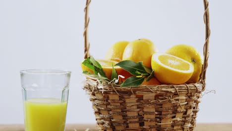 Close-up-of-sweet-limes-in-wicker-basket-and-glass-of-juice