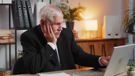 caucasian senior businessman in suit working with laptop and financial documents at home office