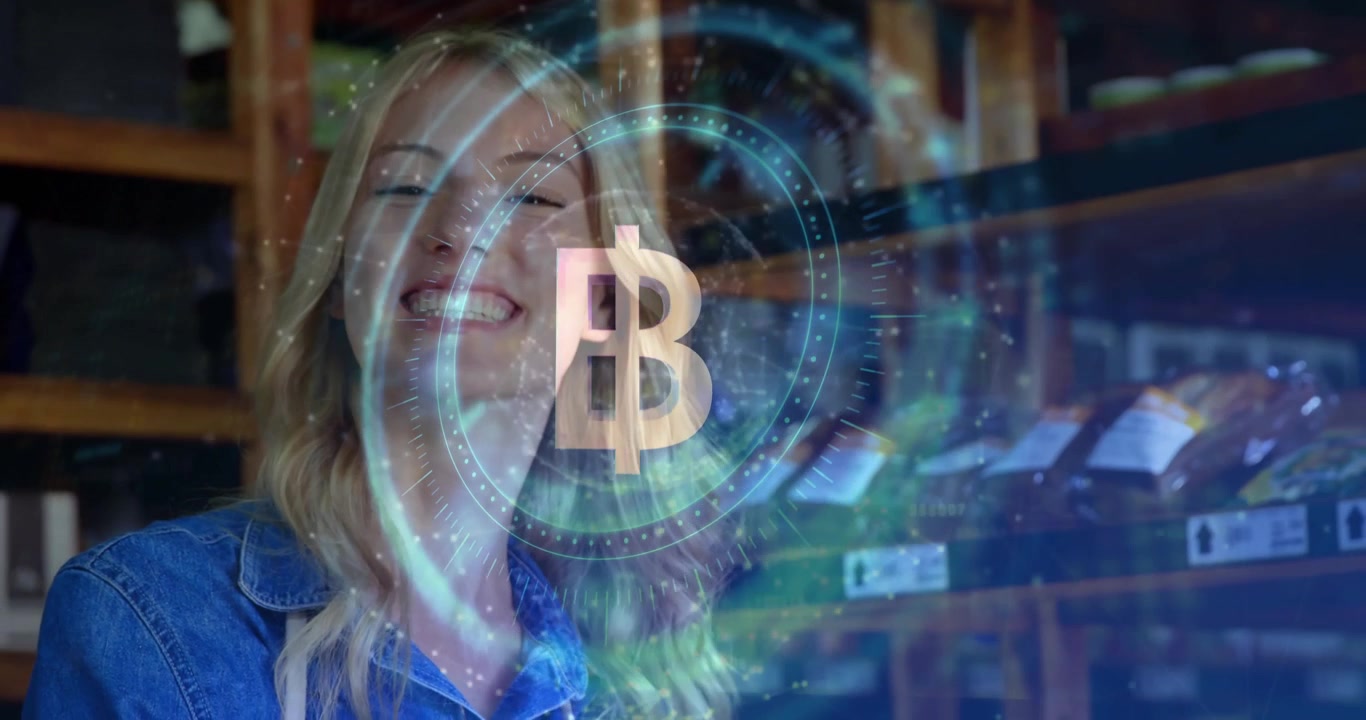 Donna in jeans in piedi e sorridente in un magazzino al dettaglio, che osserva un simbolo Bitcoin fluttuante e un'interfaccia sovrapposta.