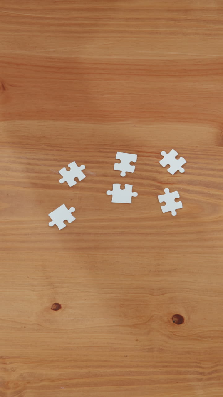 Tangan Meletakkan Potongan Puzzle Putih di Meja Kayu