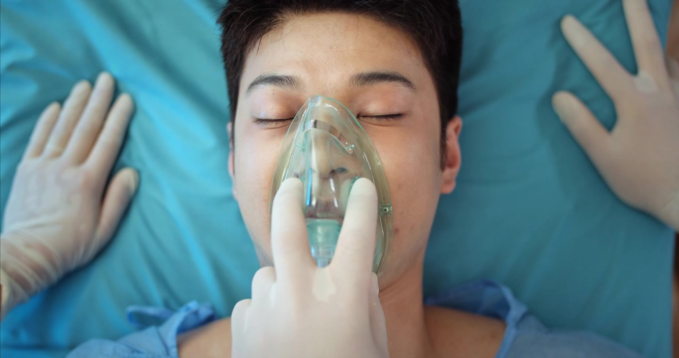 Personale medico che rimuove la maschera per l'ossigeno e controlla il polso di un paziente incosciente