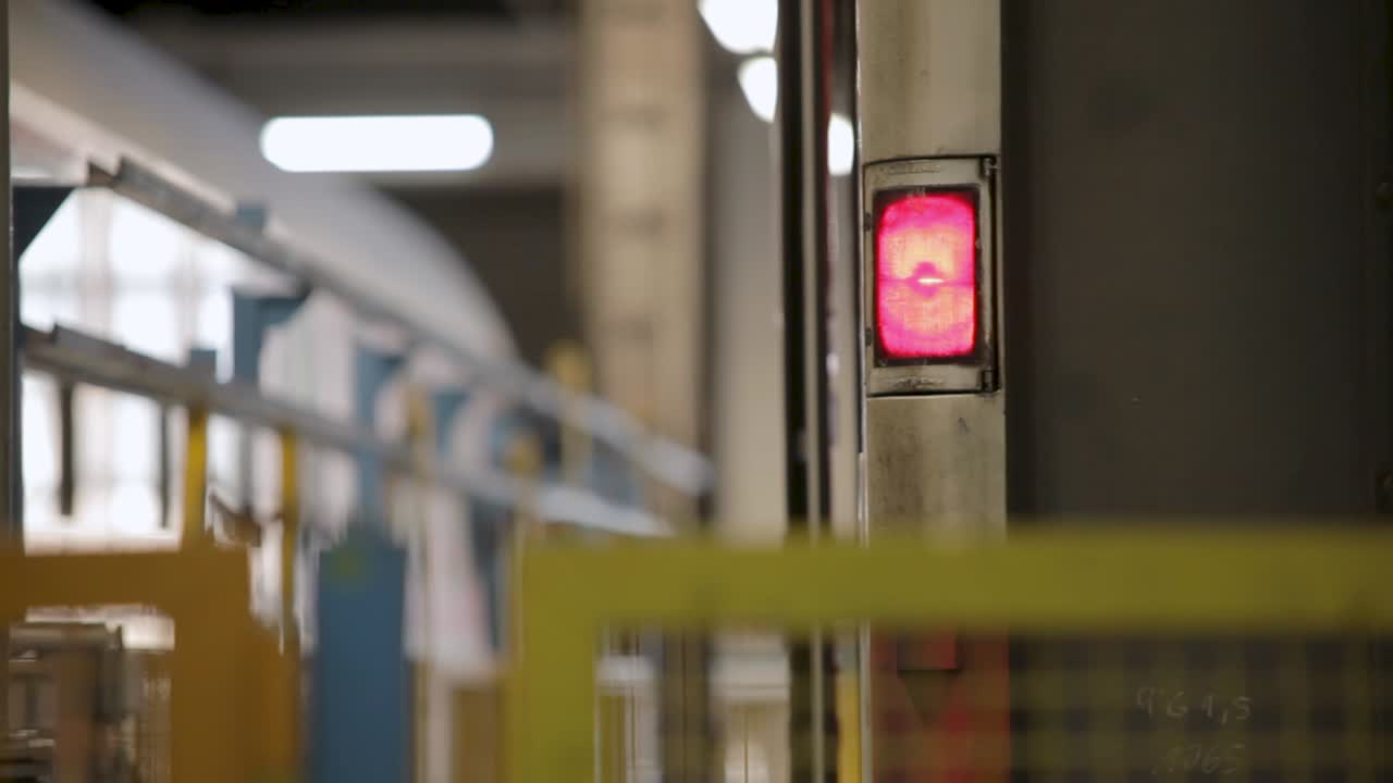 A red light blinks in a factory setting, indicating an industrial process in progress