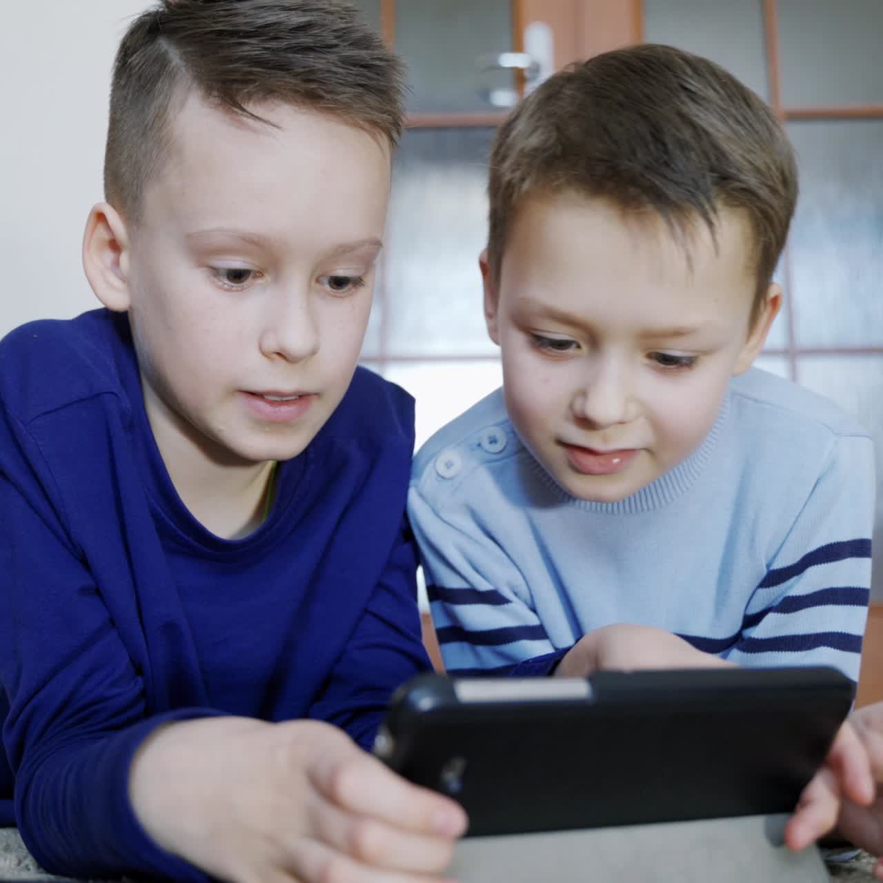 Brothers alone at home using mobile phone