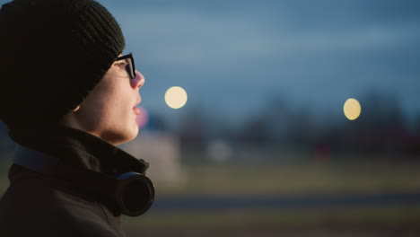 side view of a young boy in black outfit and glasses, lifting a ball with a headset around his neck, the background features a blur of light reflection