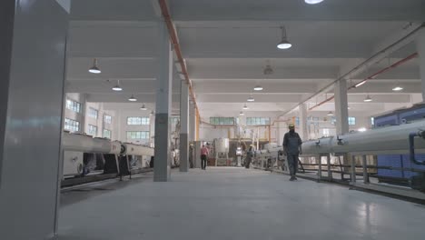 low angle view of workers in a modern pvc pipe manufacturing factory. the image showcases industrial machinery and spacious factory interiors in karachi, pakistan.