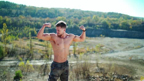 portrait of bodybuilder on nature background in summer. handsome sportsman posing on camera and showing his muscular body outdoors.