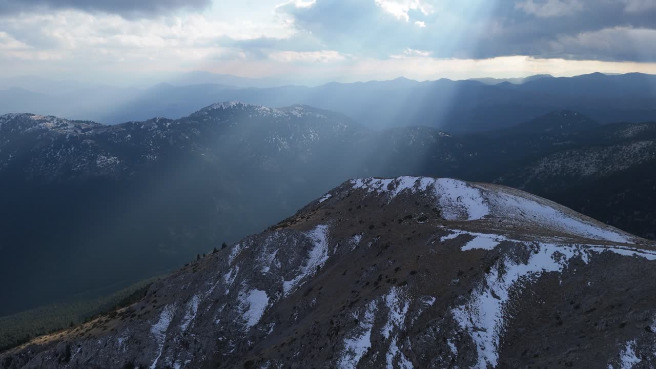 Large beam of light breaks between clouds casting down on Peloponnese mountains in winter
