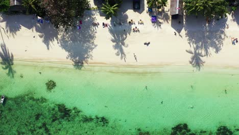 Menschen-Sonnen-Sich-Am-Exotischen-Strand-Mit-Weißem-Sand-Unter-Palmen,-Umspült-Von-Türkisfarbener-Lagune-Mit-Korallenriffen-In-Malaysia
