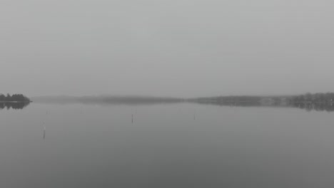 dron volando sobre un puerto de niebla invisible con boyas en la orilla
