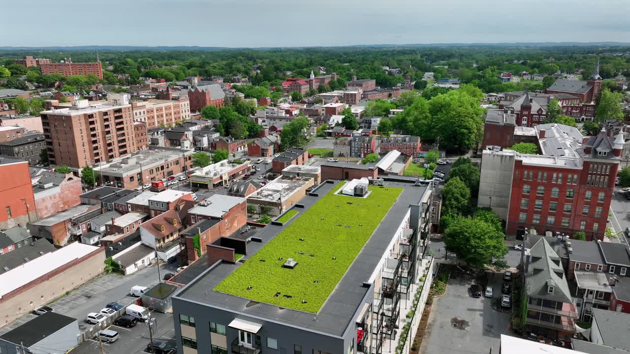 Green rooftop garden on building of American downtown. Sunny day in spring season. Red brick buildings and houses in Lancaster. ESG theme.