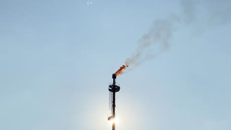 primer plano de la parte superior de la llamarada de gas con llama ardiendo y chimenea frente al sol