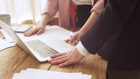 Close-Up-Of-Two-Unrecognizable-Colleagues-Debating-Using-Laptop-Computer-And-Drawing-A-Diagram-On-Paper