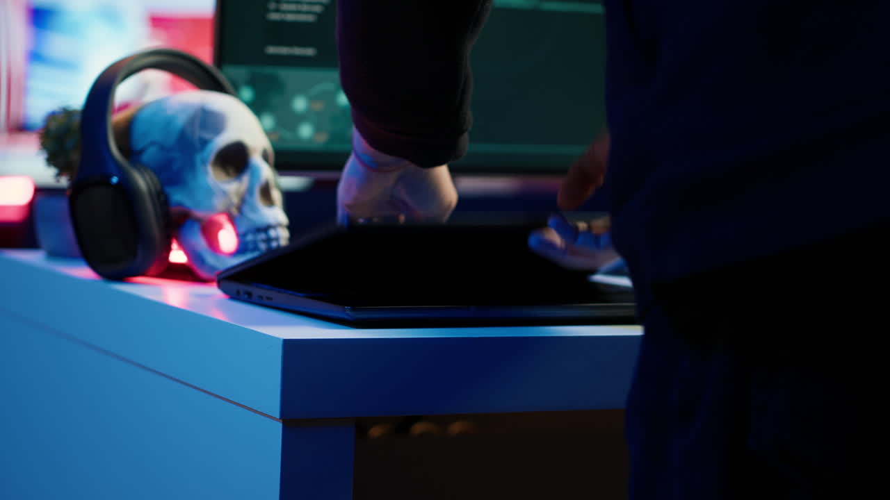 후드 해커가 가방에서 노트북을 꺼내서 ddos 공격을 준비하고 있습니다.