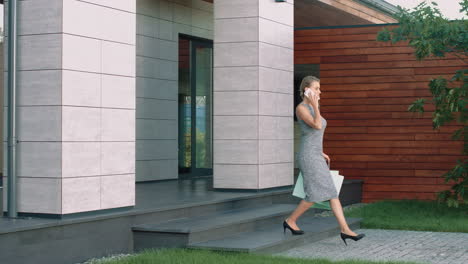 Business-woman-going-down-stairs-from-modern-building-with-shopping-bags.