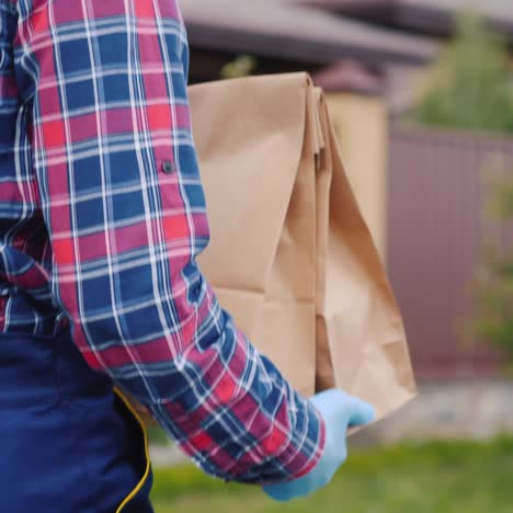 Rückansicht-Eines-Lieferservice-Mitarbeiters,-Der-Lebensmitteltüten-Zum-Kunden-Nach-Hause-Trägt