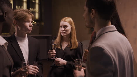 group friends wearing stylish clothes while talking and toasting with champagne glasses at new year's party