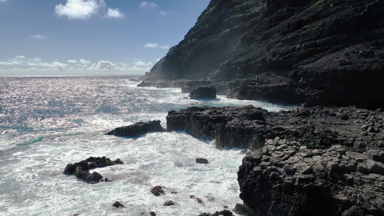 Hawaii's coast captivates with its perilous beauty, featuring towering white waves and volcanic rock