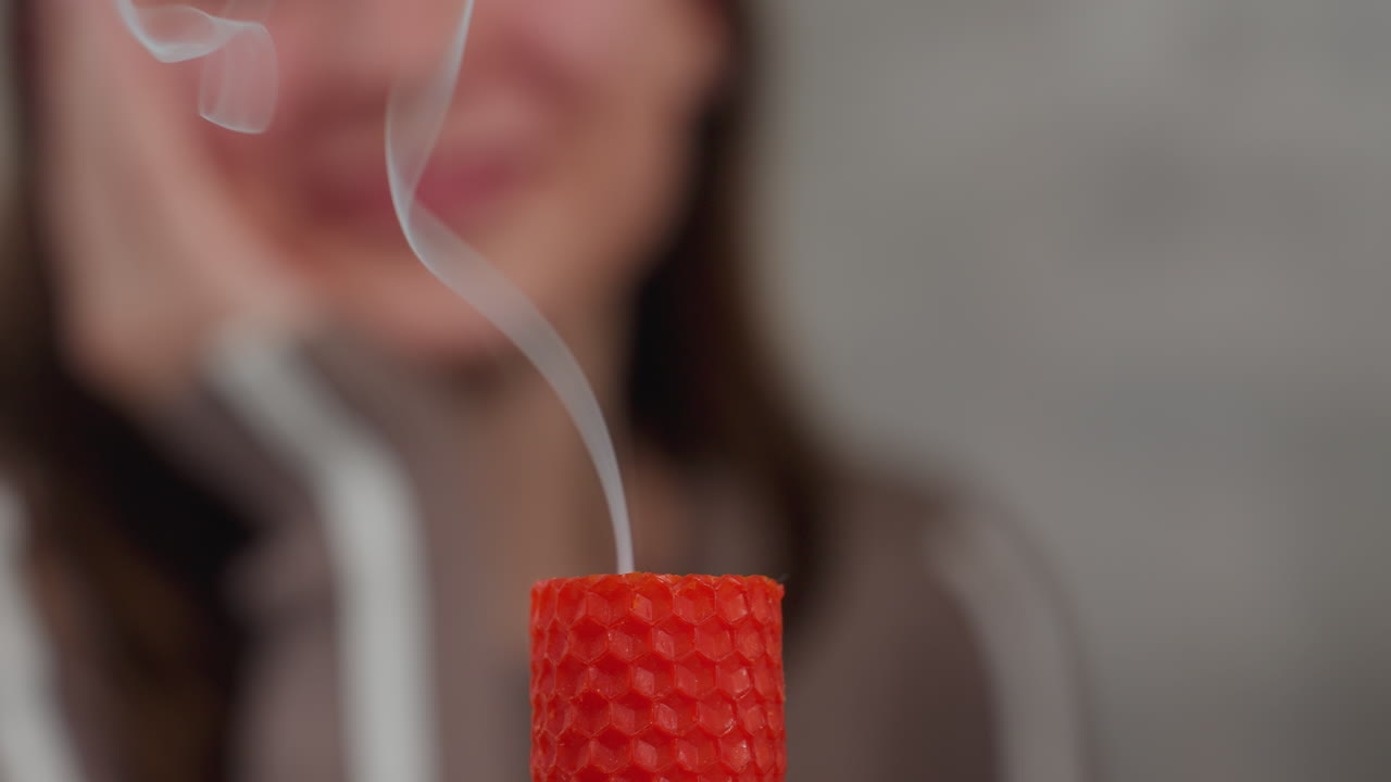 꺼진 후 미세한 연기를 방출하는 은 불의 클로즈업, 배경에서 흐릿한 인물들이 지켜보고, 부드러운 연기가 상승합니다.