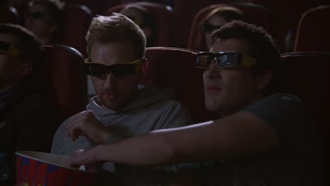 Man-eating-popcorn-in-3d-cinema.-Spectactors-enjoy-cinema-snacks