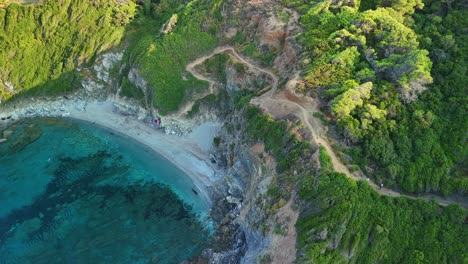una playa aislada rodeada de exuberantes colinas verdes y aguas azules claras en grecia, vista aérea
