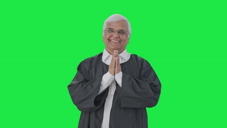 feliz abogado senior indio saludando y haciendo namaste pantalla verde