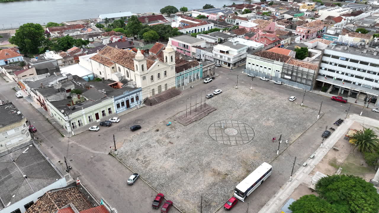 Movimento cinematografico della telecamera che si allontana e sale dalla piazza centrale della città di Jaguarao in Brasile per rivelare il ponte storico e il fiume all'orizzonte