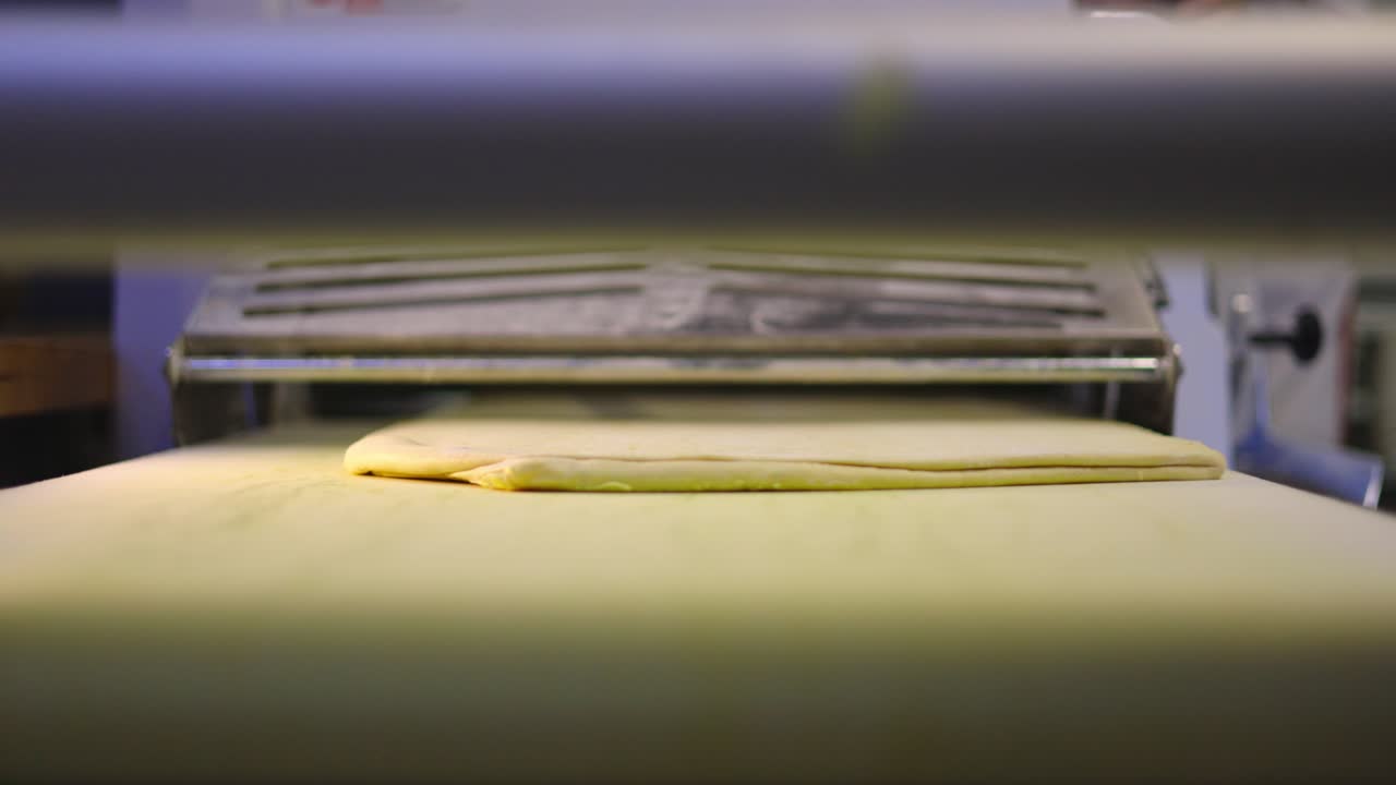 Dough rolls on the conveyor belt of the pastry machine to be rolled out ready for dessert