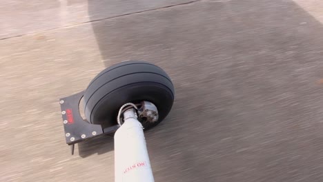 isolated view of aeroplane wheel, landing gear, as seen from small aircraft window plane traveling along runway, close up