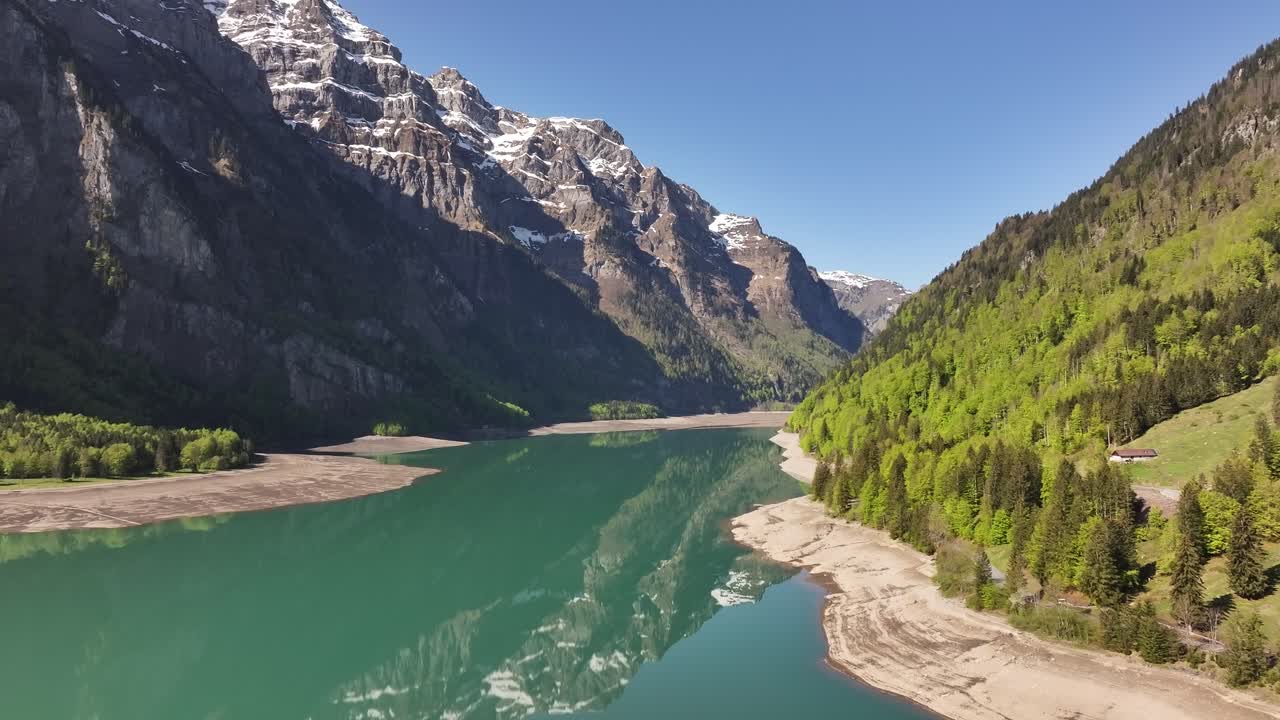 Aerial Klöntalersee lake with snow peaks and forested hills in Glarus Switzerland