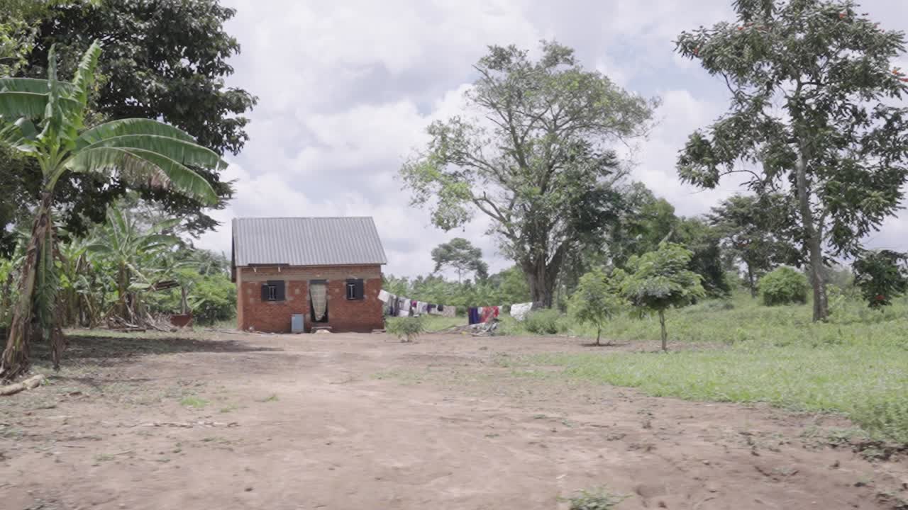 A slow-motion shot passing by a small hut in rural Uganda, Africa