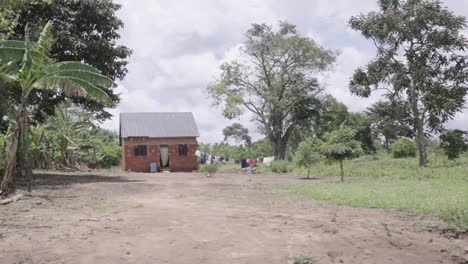 a slow-motion shot passing by a small hut in rural uganda, africa