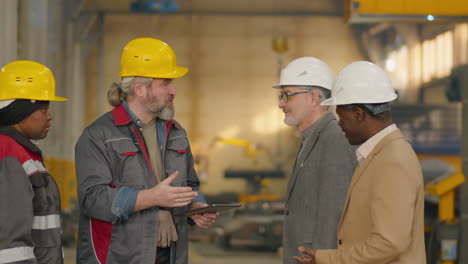 multiethnic engineers shaking hands and talking in factory