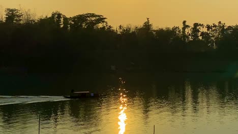 a sunset view of surma river bangladesh - a traditional wooden boat is crossing the surma river at the downtime in bangladesh in the evening