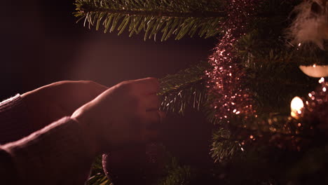 Woman's-hands-hanging-ornament-ball-decoration-on-Christmas-tree